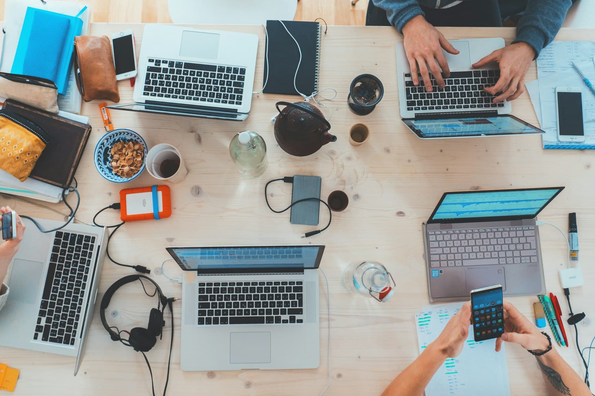 Vista aerea de un escritorio compartido con varias laptops y telefonos, equipo trabajando con herramientas digitales