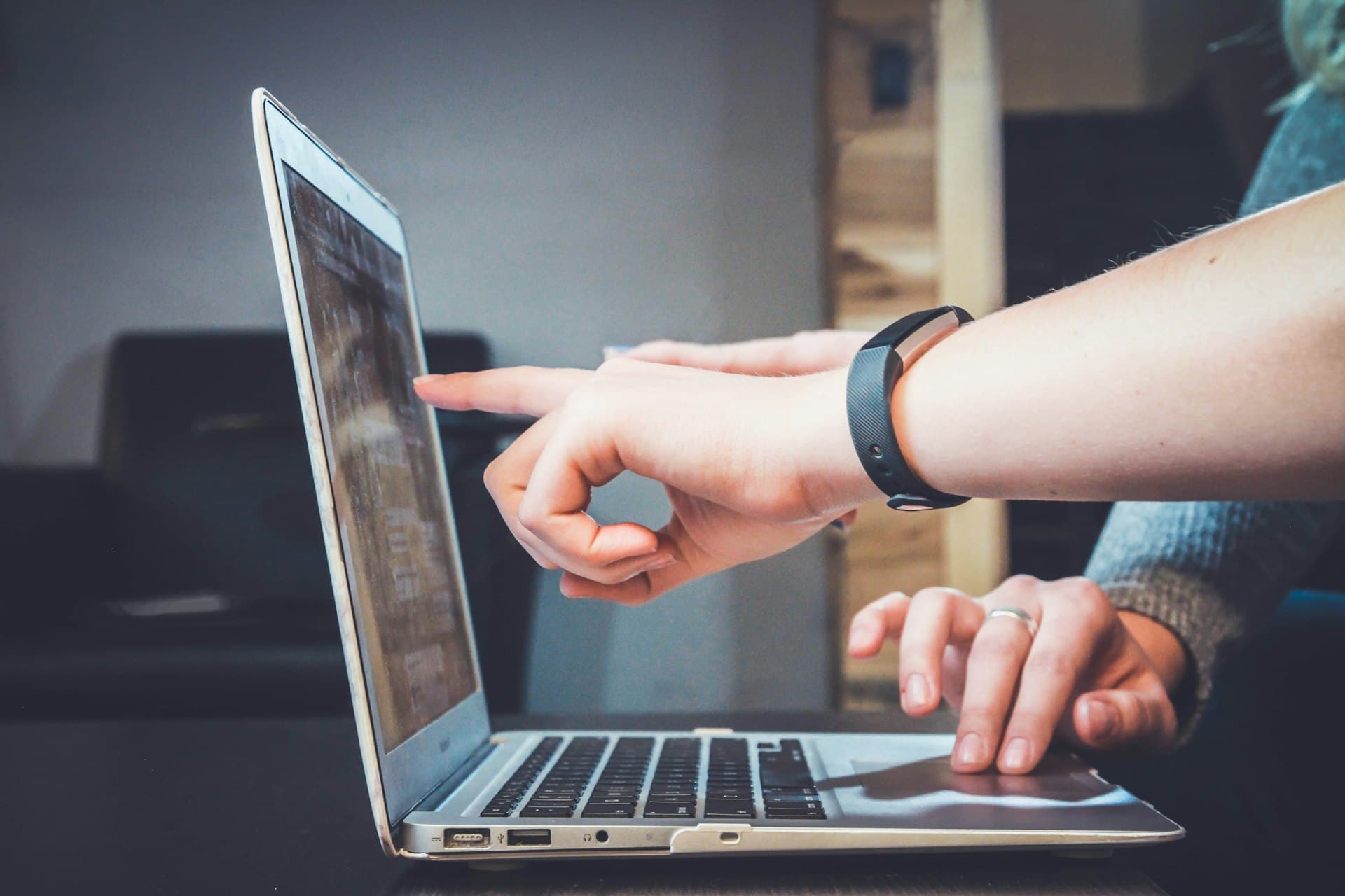 Dos personas señalando y revisando datos en la pantalla de una laptop